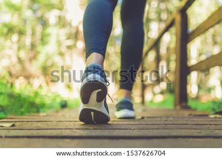 Close up of female legs with running shoes on wooden footpath in woods. Nature and sport healthy lifestyle concept. Royalty-Free Stock Photo #1537626704
