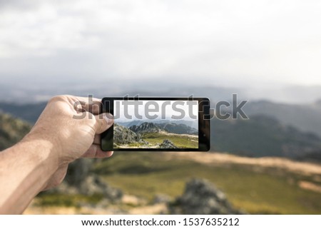 Taking a picture of a landscape grabbing the cell phone with one hand