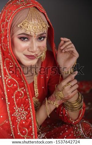 Beautiful hijab girl wearing red traditional India costume lehenga choli or saree with kundan jewelry set isolated over grey background. Deepavali celebration and Bollywood concept