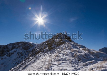 Top of snow-capped Seceda mountain in the Italian Dolomites in sunny weather with blue sky and clouds. The lens reflexes are also shown.