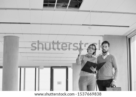 Black and White Photo of an Attractive Real Estate Agent Client Man and business woman standing together in an open plan empty office