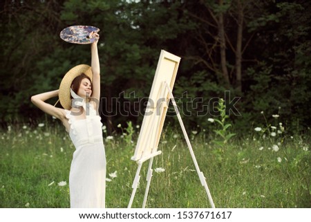 young beautiful slim woman in a forest glade draws a picture