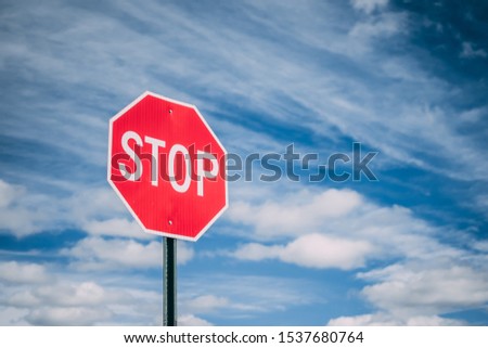 Stop Sign Against Cloudy Blue Sky
