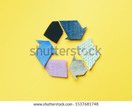 Reuse, reduce, recycle concept background. Recycle symbol made from old clothing on yellow background. Top view or flat lay. Royalty-Free Stock Photo #1537681748