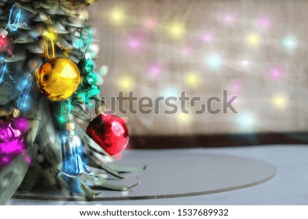 Original Christmas tree concept. Various colorful shiny glass Christmas balls hangs on the leaves of an inverted ripe pineapple. Copy space for your text.