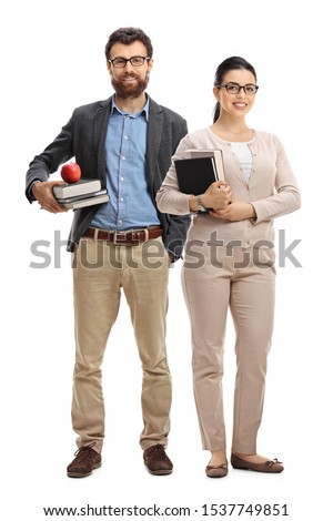 Full length portrait of a male and female teacher standing and holding books isolated on white background