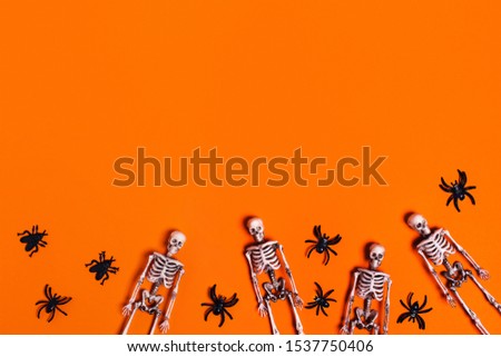 Halloween decoration concept - orange background with spiders, bats, skeletons. Flat lay, top view. Place for your text.