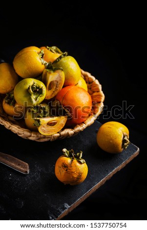 Sweet small persimmons on the black background, selective focus