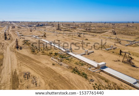 Aerial view of field of oil pumps. Pumpjack. Oil industry equipment. Rig energy machine for petroleum crude. Daylight, morning, blue sky. USA