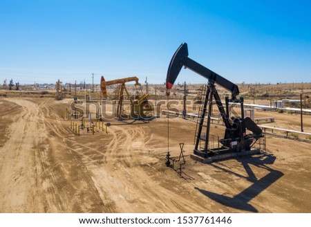 Black and yellow oil pumps. Pumpjack. Oil industry equipment. Rig energy machine for petroleum crude. Daylight, morning, blue sky. Aerial view. USA