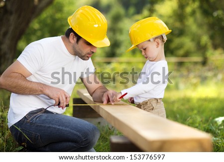 Little son helping his father with building work Royalty-Free Stock Photo #153776597