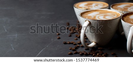 white cups of coffee on a table in a cafe with coffee beans, latte art panorama
