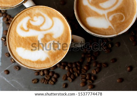 close-up of a flower drawing on coffee, latte art on a background of coffee beans on a marble table