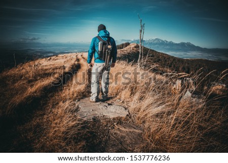 Traveler tourist photographer stands and admires the view of the mountains. Landscape photographer observes the mountain panorama. Warm filter and vignetting.