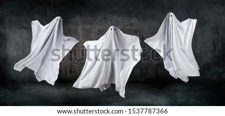 Ghosts in sheets dancing and floating in the air Royalty-Free Stock Photo #1537787366