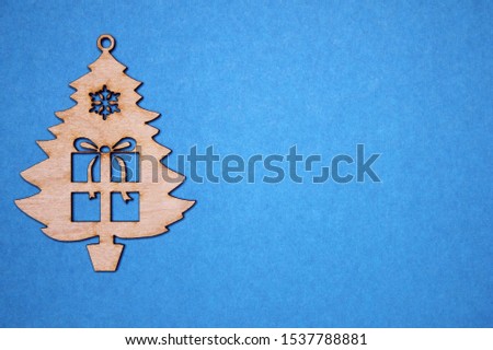 Wooden Christmas tree figurine with a gift on a blue background. Copy space.