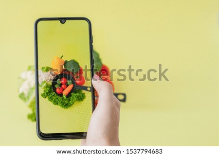 Girl taking picture of vegetarian food on table with her smartphone. Vegan and healthy concept