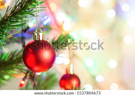 Christmas decoration. Hanging red balls on pine branches Christmas tree garland and ornaments over abstract bokeh background with copy space
