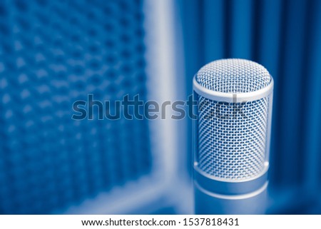 professional microphone in sound recording studio, blue acoustic foam background