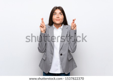 Young business woman over isolated white background with fingers crossing and wishing the best