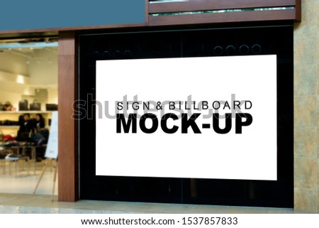 Mock up large blank billboard on the wall near entrance of fashion shop with clipping path, Empty signboard for information or promotion advertising at shop, blurred people in background