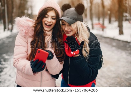 Fashionable girls in a winter city. Stylish ladies in a cute jackets. Woman use the phone
