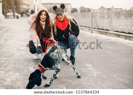 Fashionable girls in a winter city. Stylish ladies in a cute jackets. Women with a dalmatian