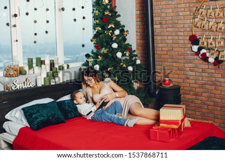Beautiful mother in a white sweater. Family with cristmas gifts. Little boy near christmas tree