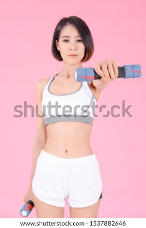 sport woman standing doing exercise for arms with dumbbells and showing muscle bodybuilding on pink backgrounds, fitness concept, sport concept