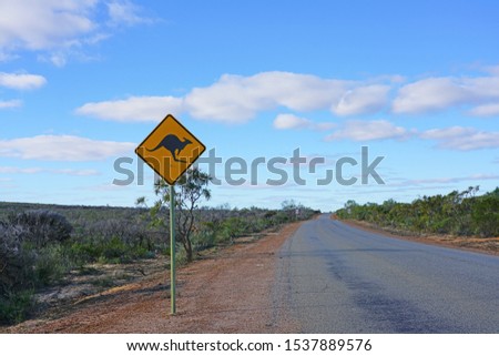 A yellow kangaroo crossing road sign on the road in Western Australia