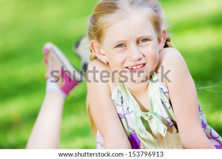 Image of little cute girl lying on grass in park