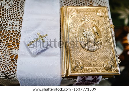 Holy Bible decorated with gold and icons, Wedding crowns stand on the table in church. Close up. Divine Liturgy.