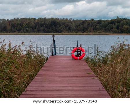 wooden plank pier with grassland floating ring on wooden bench forest in background overcast cloudy day