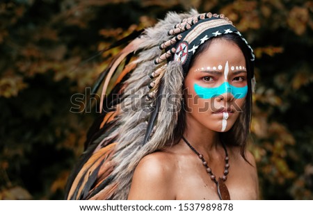 The abstract art design bakcogrund of  beautiful woman wearing headdress feathers of birds. American Indian girl in native costume,posing in forest,vintage and art tone,blurry light around