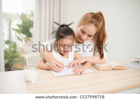 happy Little girl looking at book with her mother