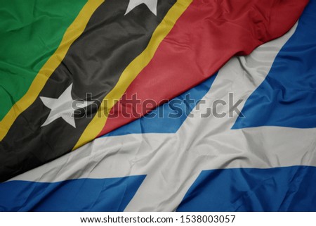 waving colorful flag of scotland and national flag of saint kitts and nevis. macro
