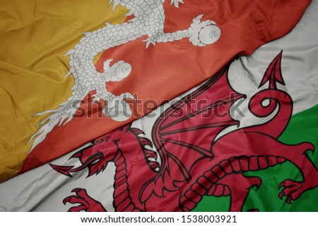 waving colorful flag of wales and national flag of bhutan. macro