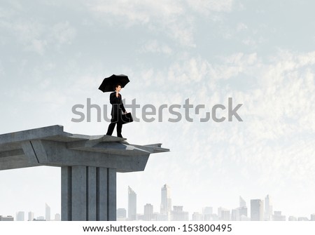 Image of businessman with umbrella standing at the edge of bridge