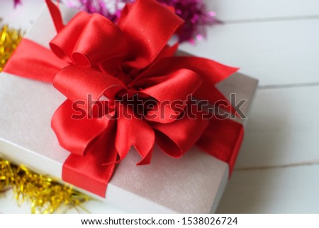 Silver gift box with red ribbon and colorful of the streamer on white wooden background. Top view. Christmas's day, New year party concept.