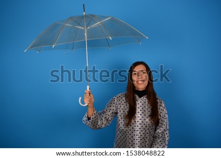 smiling woman holds umbrella on blue background rain bad weather