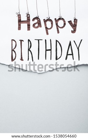 Sheet of paper with words HAPPY BIRTHDAY on light grey background, top view. Space for text