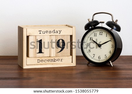 Wood calendar with date and old clock. Tuesday 19 December