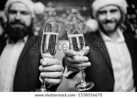 Business people drink champagne at party. Colleagues celebrate new year. Men formal suits and santa hats hold champagne glasses. Cheers concept. New year corporate party. Party with champagne.