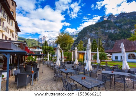 Kandersteg, Switzerland street view with cafe, restaurant in swiss village and mountains autumn panorama behind Royalty-Free Stock Photo #1538066213