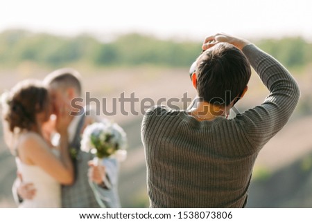 wedding photographer takes pictures of couple in nature in autumn, the photographer in action