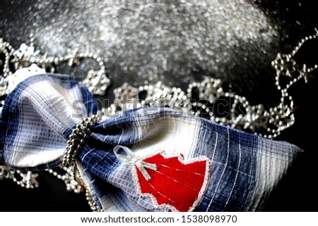 Black background with silver sequins, gift bag with red Christmas tree