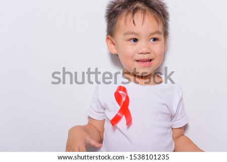 Closeup of boy kid with red ribbon Support HIV AIDS on shirt, World AIDS Day and medicine concept with copy space for use white background