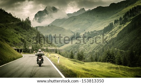 Motorcyclist on mountainous highway, cold overcast weather, Europe, Austria, Alps, extreme sport, active lifestyle, adventure touring concept Royalty-Free Stock Photo #153813350