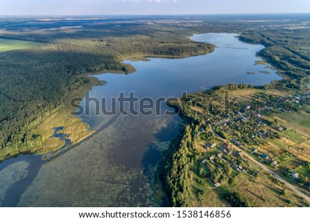 Beautiful aerial shot of a large forest lake. Summer landscape with the setting sun. Typical view for the Central European plain.
