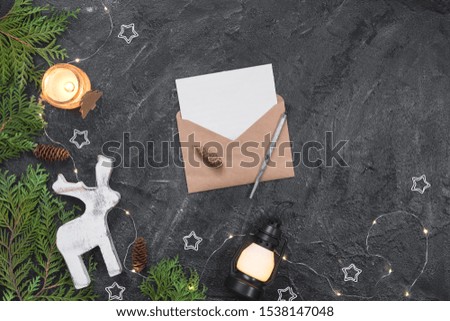 Christmas composition. Gifts, envelope, fir tree branches, white decorations on black background.